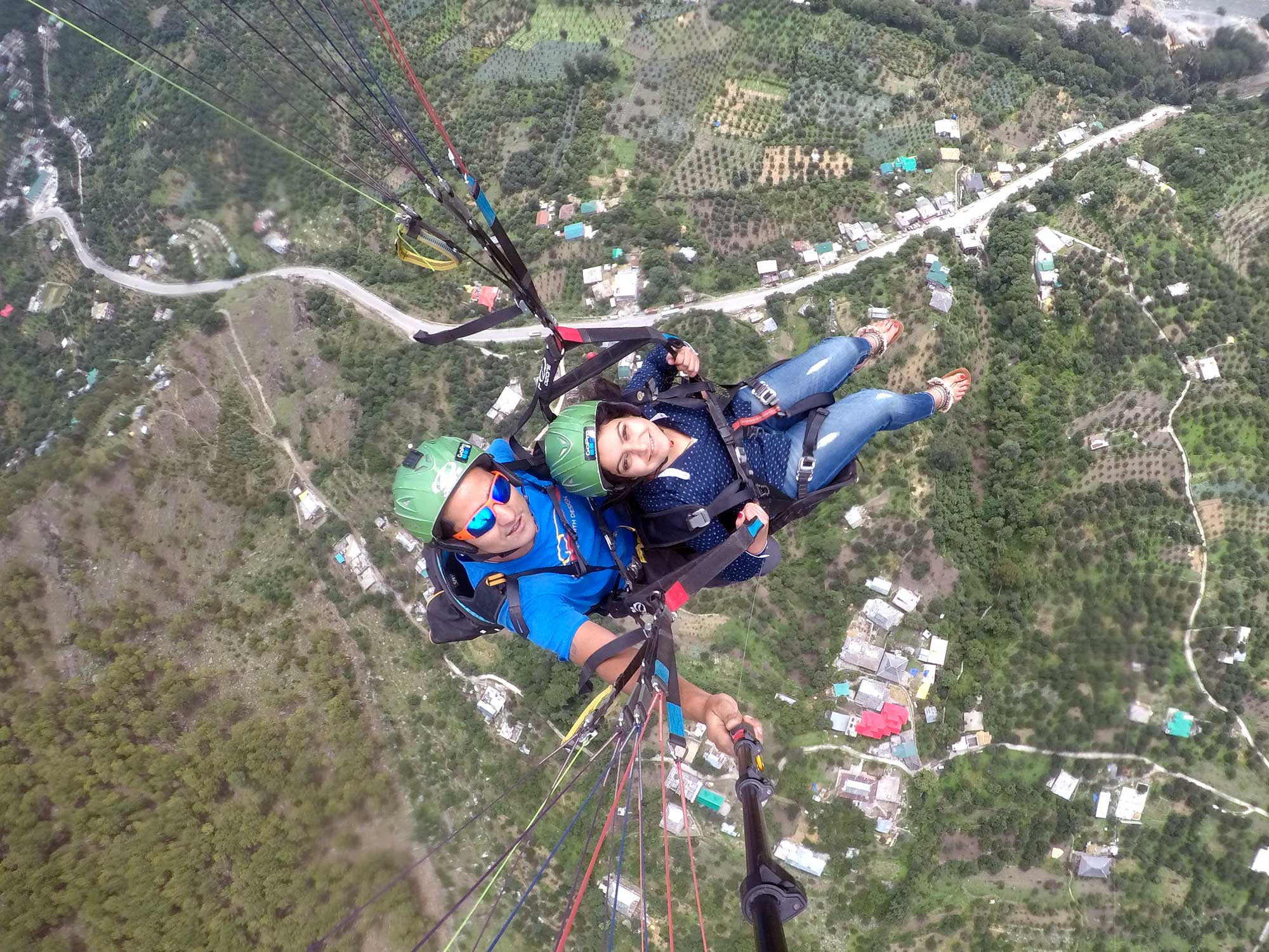 A person paragliding high above the snow-capped mountains and green valleys of Solang Valley, Manali