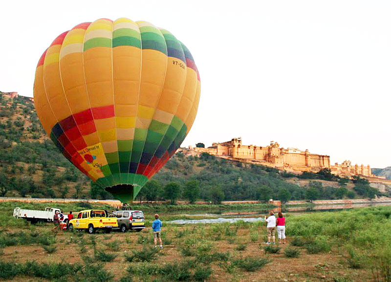 Colorful hot air balloon flying over the historic Amber Fort and mountains in Jaipur, Rajasthan