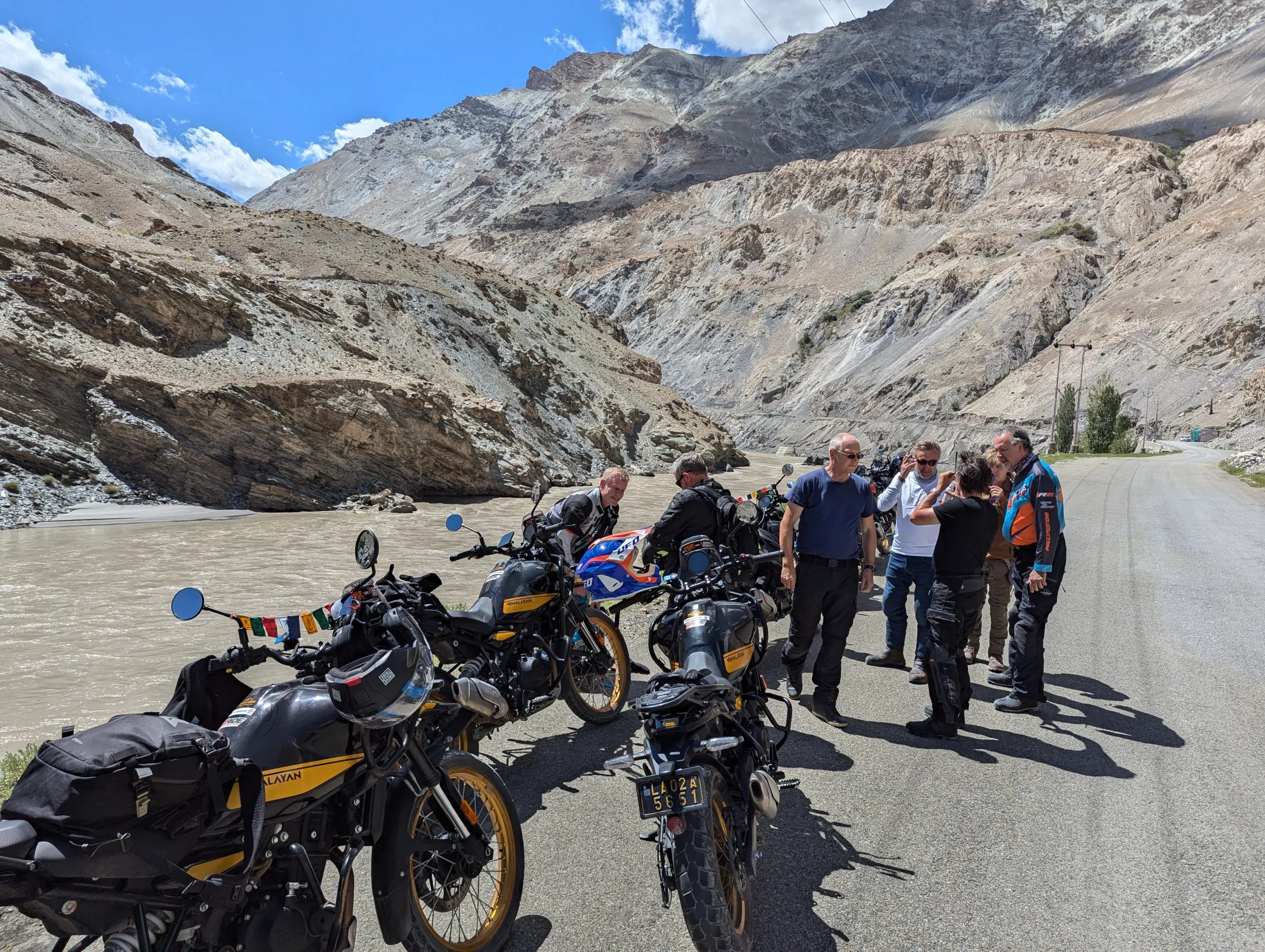A group of bikers riding Royal Enfield motorcycles near the blue waters of Pangong Lake in Ladakh